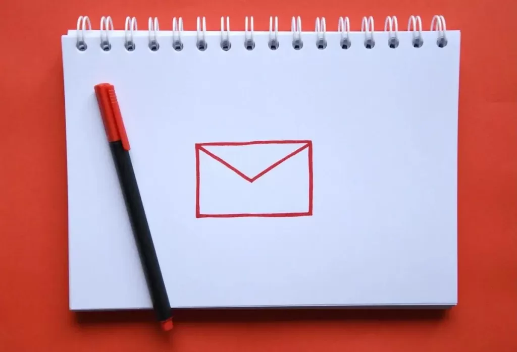 Desenho de um envelope vermelho em um caderno com uma caneta preta e vermelha sobre fundo vermelho.